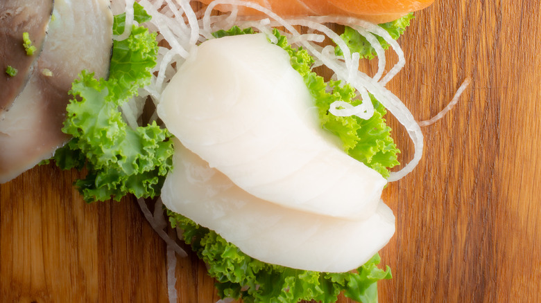 white fish sashimi on bed of lettuce