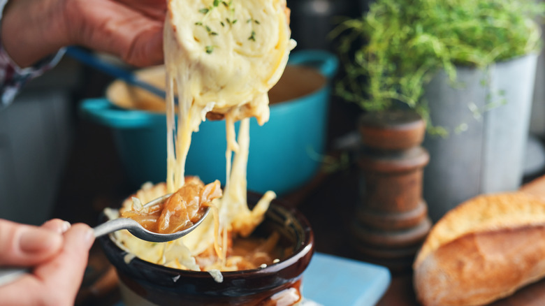 Hands scooping French onion soup