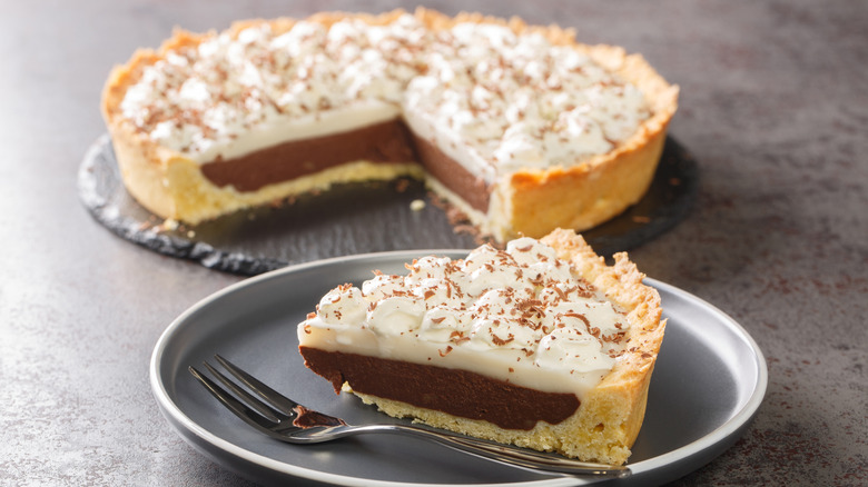 Full haupia pie with a cut-out slice foregrounded on a plate