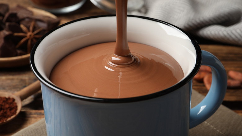 A thick stream of hot chocolate pours into a mug