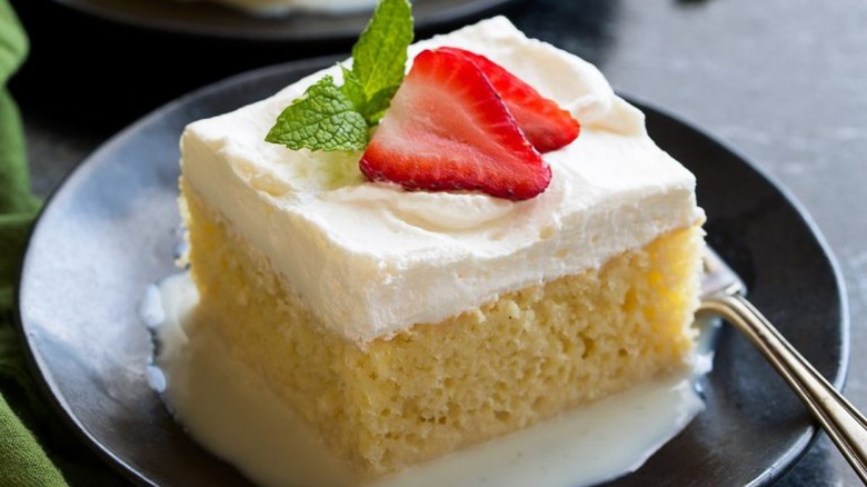 a slice of tres leches topped with strawberries on a plate