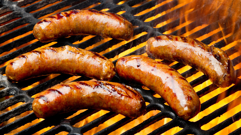 Plump sausages or hot dogs roast on a fiery grill