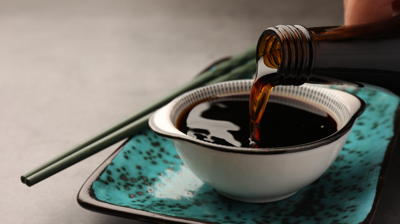 Soy sauce being poured into a bowl on blue plate