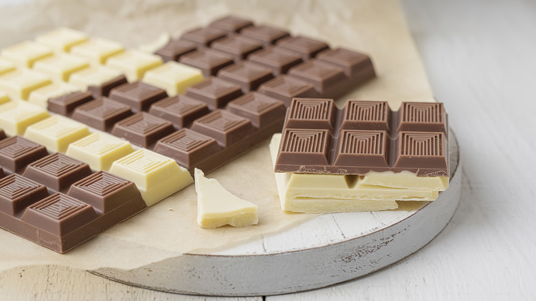 Bars of white and milk chocolate on a white wooden board