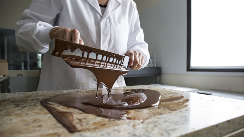 Person spilling melted chocolate onto countertop