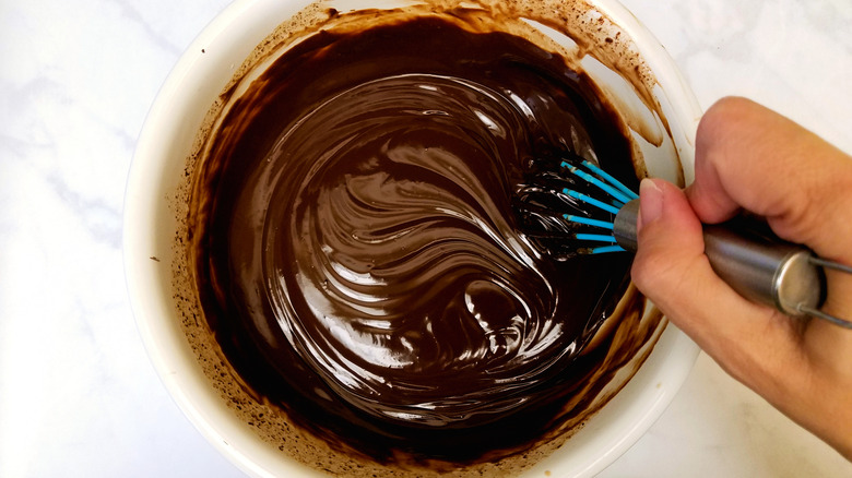 Hand whisking a bowl of chocolate ganache