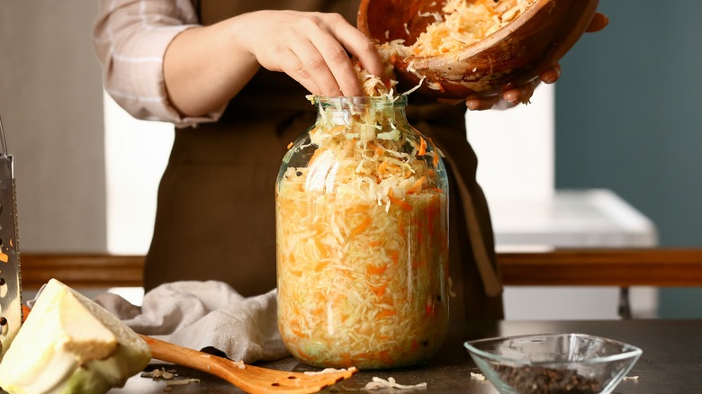 Woman stuffing jar with shredded cabbage