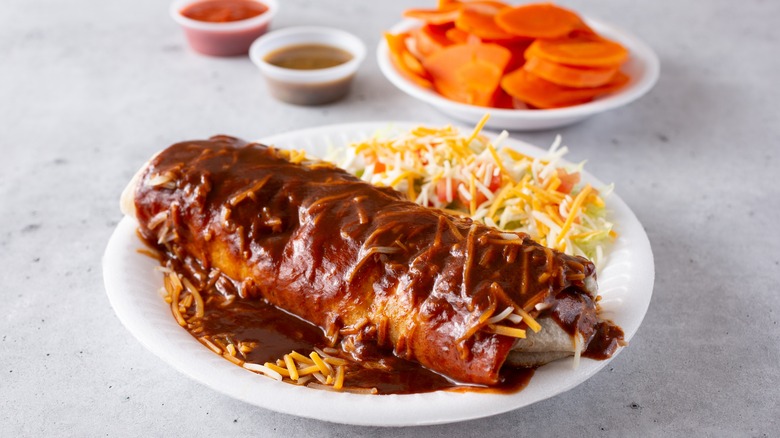 Wet burrito in red sauce and cheese with spicy carrots and salsa