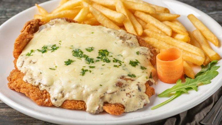 Schnitzel under cheese sauce with fries