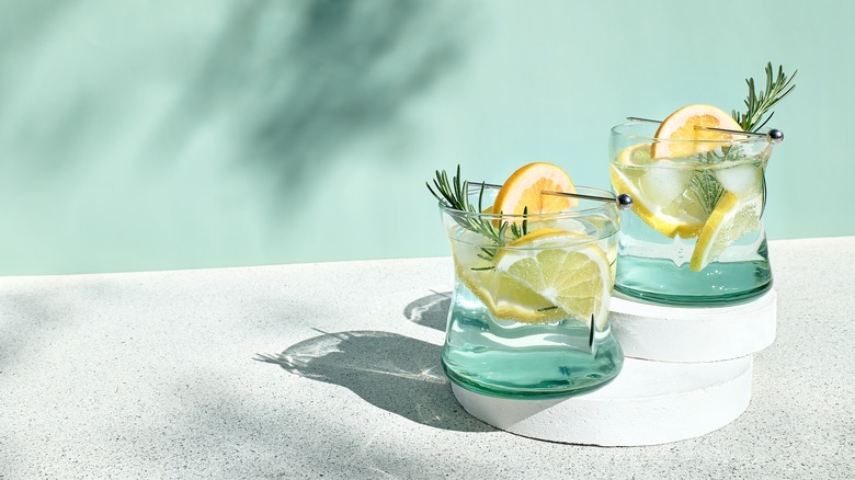 two cocktails with lemon wedges and rosemary sprigs