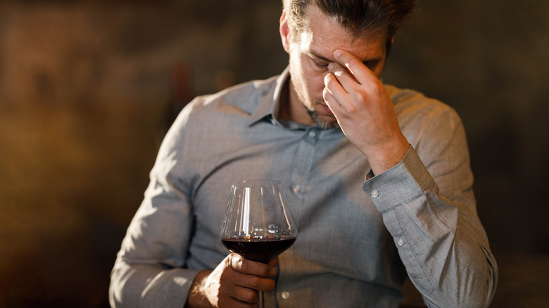 person drinking wine looking displeased or unwell 