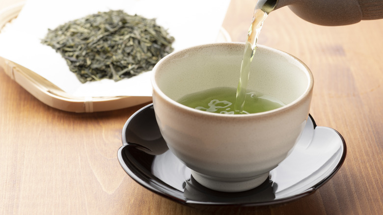 Green tea being poured in a cup