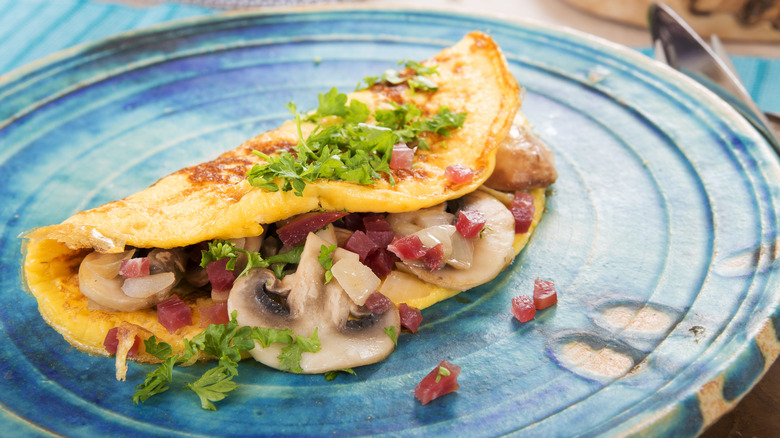 An omelet with vegetables is on a blue plate.