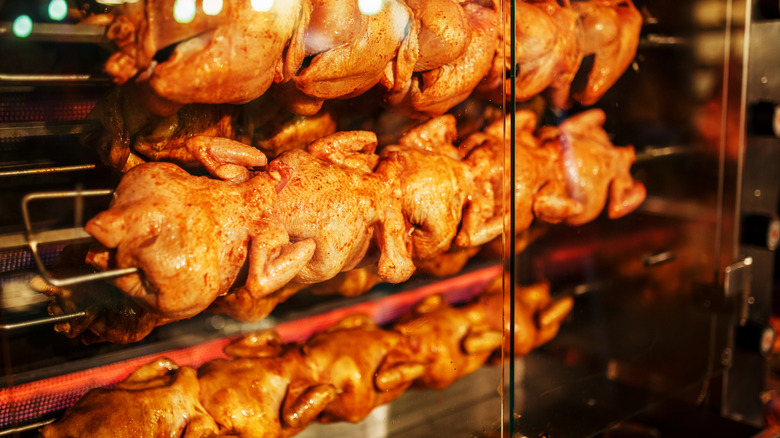 Rotisserie chickens roasting in industrial oven