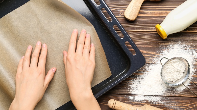 Woman laying parchment paper on baking sheet