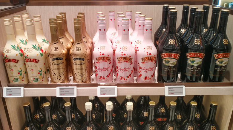 A display of Baileys liqueurs including Colada, Chocolat Luxe, Strawberries and Cream, and the Original Irish Cream, arranged on shelves