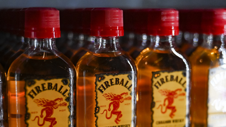 A row of bottles Fireball Whisky bottles sit in a store display case