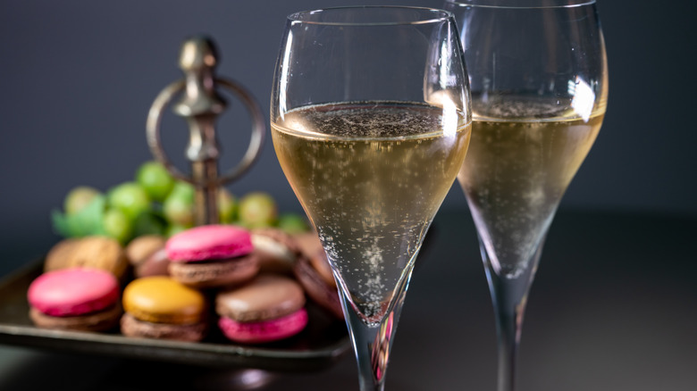 Two glasses of sparkling wine with macarons in the background