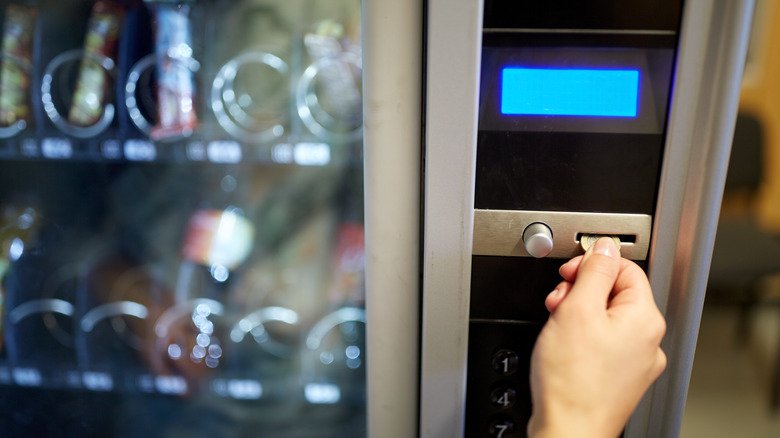 Hand putting coins into vending machine