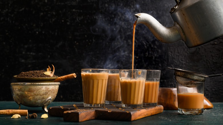 Kettle pouring indian chai into glasses