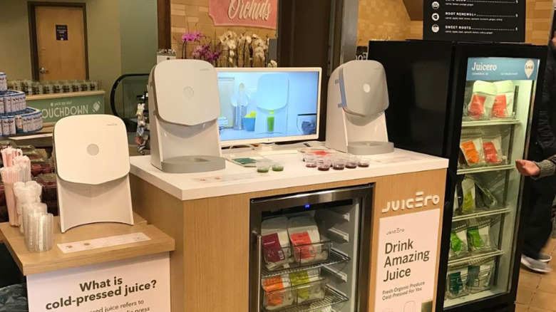 A Juicero machine display in Whole Foods with juice presses, packets, and samples