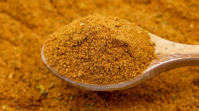 a wooden spoon scooping up cajun spice mix