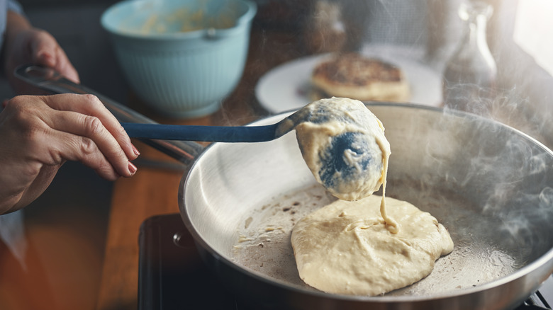 ladle adding pancake batter to pan