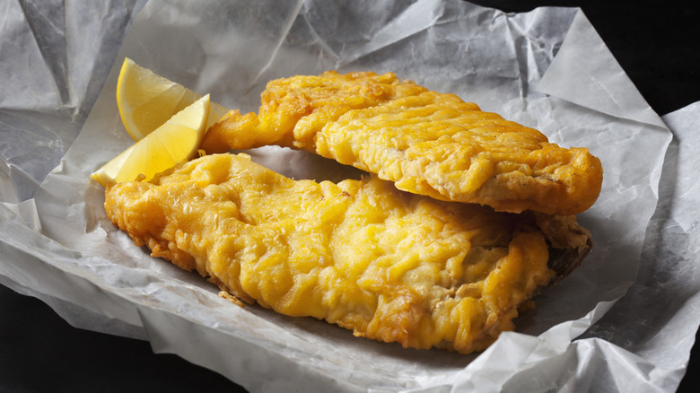 Fried fish in a paper-lined basket with lemon wedges