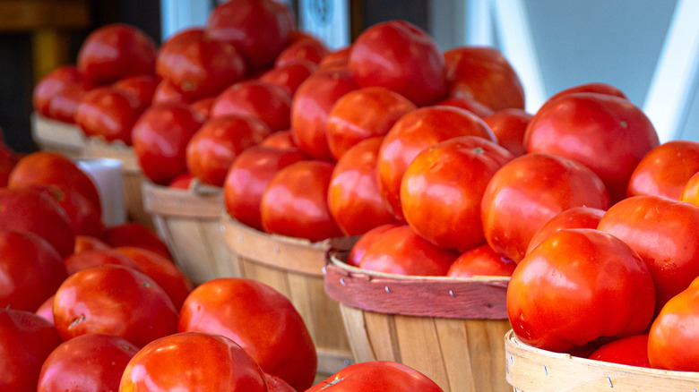 Beefsteak tomatoes sit in wooden bins at a farmer's market