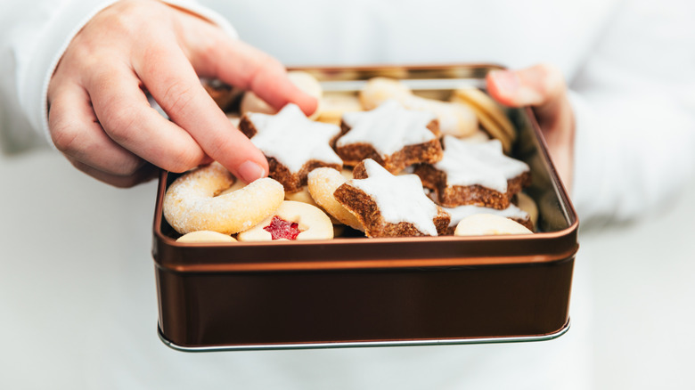 Person holds square cookie tin full of Chanukah cookies