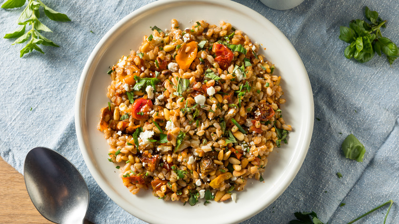 Farro grain salad on a white plate made with tomatoes, feta cheese, and fresh herbs