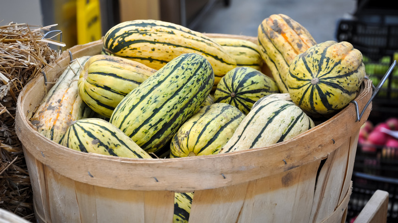 A pile of delicata squash in a basket at a market