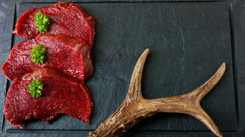 Slices of fresh roe deer next to an antler