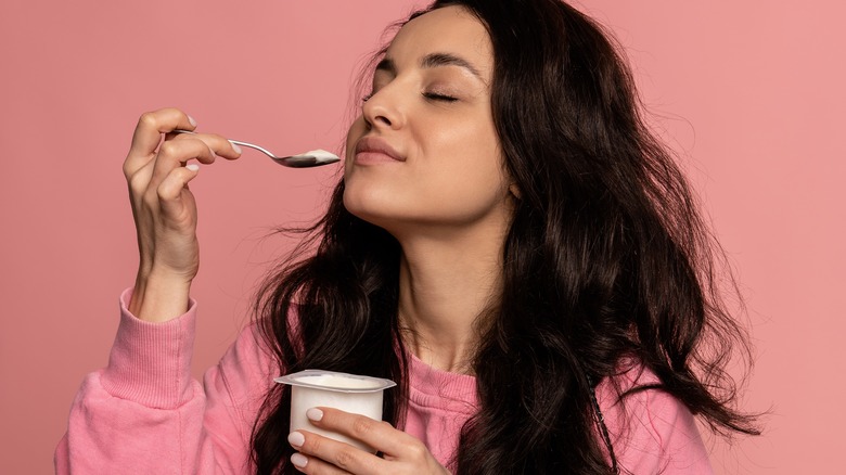 woman smelling spoonful of yogurt