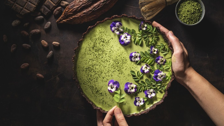 Matcha tea and chocolate tart with moringa leaves, nuts, and edible flowers