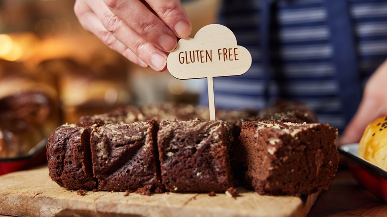 A baker puts a Gluten Free sign in a display of brownies