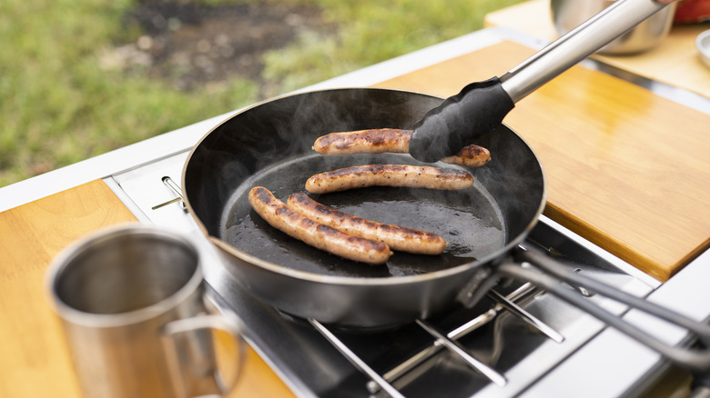 Cooking sausages on an outdoor stovetop