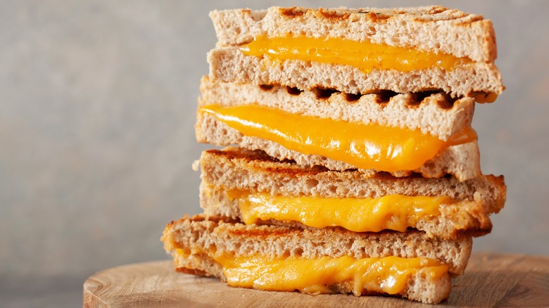 Stack of halved grilled cheese sandwiches on wooden board