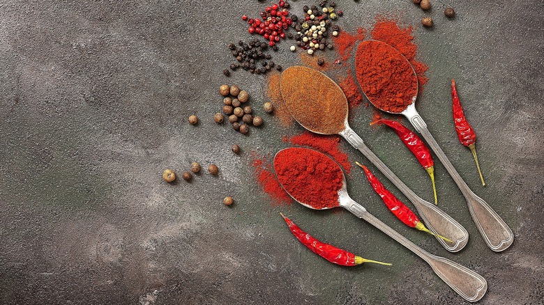 Three spoons full of ground spices like cayenne pepper and smoked paprika