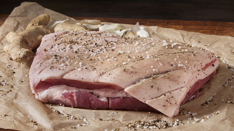 A raw slab of pork belly with its skin scored