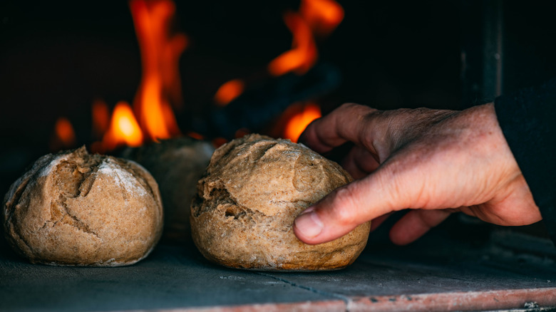 Taking loaves of homemade bread out of pizza oven