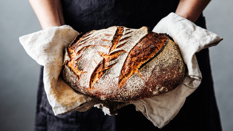 Woman holding hot artisan rustic loaf of bread