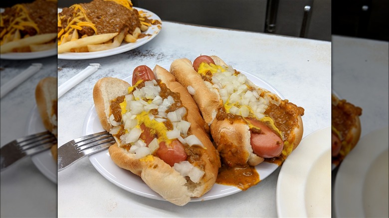 Two Coney dogs on a plate with fries on a counter