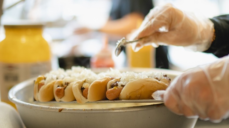 Server putting sauce on Coney dogs at Fort Wayne's Famous Coney Island