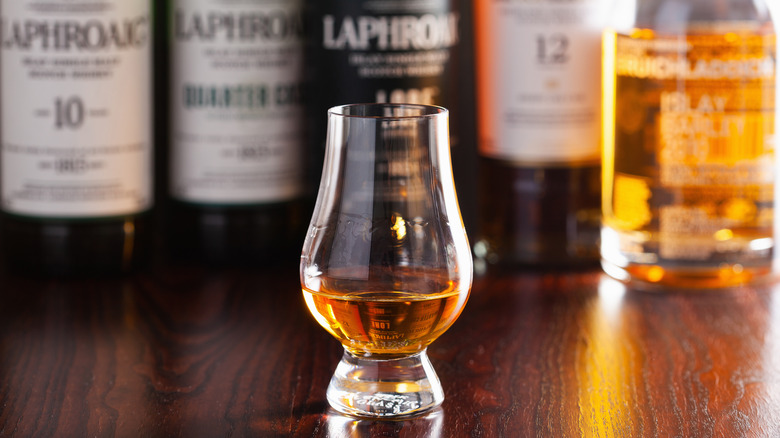 Glass of peaty Scotch whisky with Laphroaig bottles
