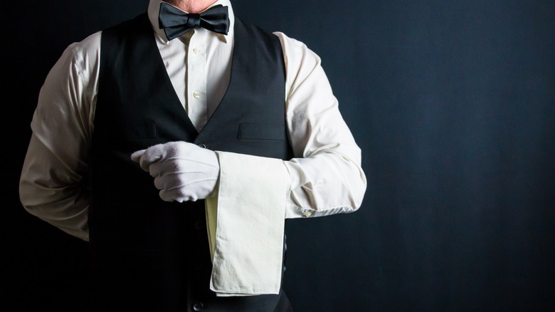 Formal waiter in white gloves and black bowtie