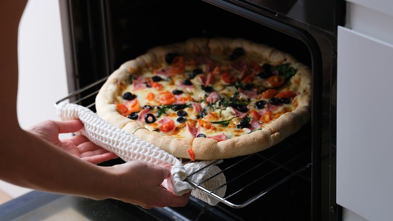 A cooked pizza being placed in an oven