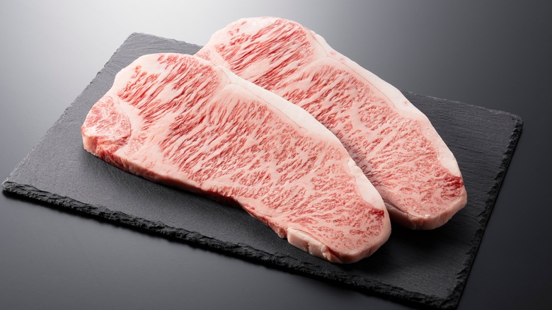 Raw well-marbled Wagyu steaks on a board