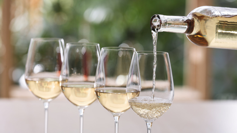 Bottle of white wine being poured into glasses