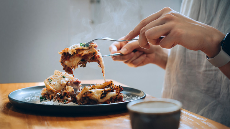 Close up of a woman eating lasagna